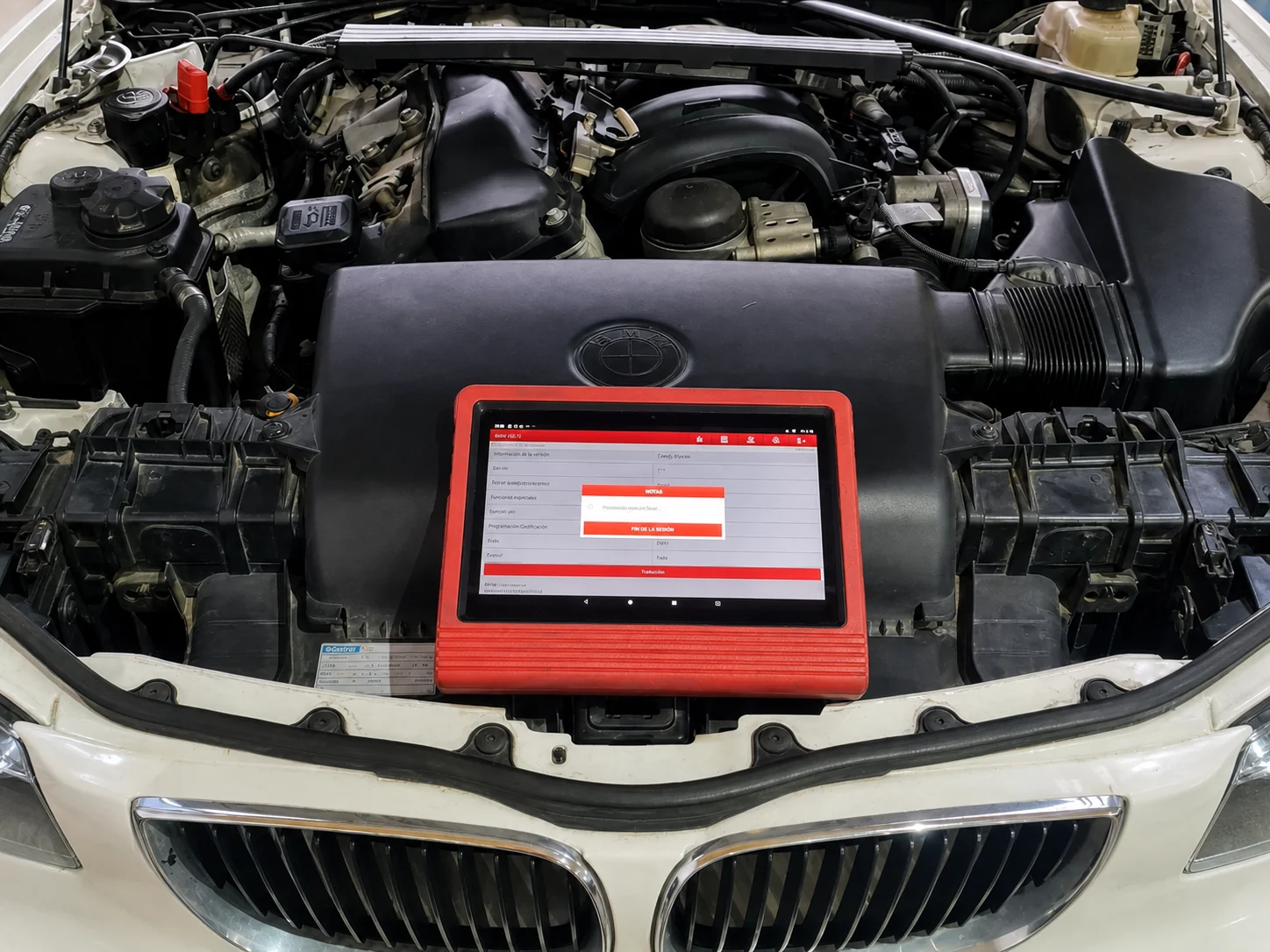 Scanner profesional sobre el motor de un BMW durante un diagnóstico electrónico